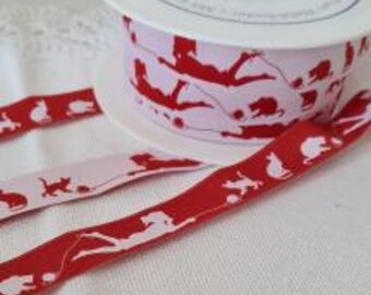 Könnte beinhalten: Eine Bandrolle mit einem sich wiederholenden Muster aus roten Katzen-Silhouetten auf hellrosa Hintergrund. Zwei Bandstücke sind abgerollt und zeigen das gleiche Design. Die Rolle liegt auf einer weißen Oberfläche.