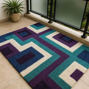 Puede incluir: Una alfombra rectangular con un patr&oacute;n geom&eacute;trico en tonos de azul, turquesa, morado y crema. La alfombra est&aacute; colocada sobre una superficie embaldosada. El dise&ntilde;o presenta l&iacute;neas y formas que se cruzan. Se ve una maceta y una barandilla de balc&oacute;n.