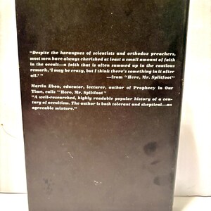 Puede incluir: La contraportada de un libro con un fondo marr&oacute;n oscuro. El texto blanco incluye citas e informaci&oacute;n del autor. El t&iacute;tulo del libro es "Here, Mr. Splitfoot". El libro trata sobre ocultismo.