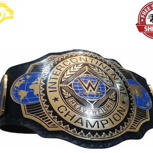 Puede incluir: Un cinturón de lucha Intercontinental Heavyweight Champion dorado y negro. El cinturón presenta un gran emblema central con el logotipo de la WWE, rodeado de texto y elementos decorativos. Hay diseños de mapas del mundo azules y dorados.