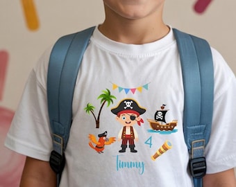 Könnte beinhalten: Weißes T-Shirt mit einem farbenfrohen Piratenmotiv. Das Design zeigt einen Piraten, ein Schiff, einen Papagei und die Zahl 4. Der Name "Timmy" steht in blauer Schrift darunter. Der Junge trägt einen blauen Rucksack.