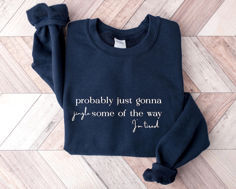 Puede incluir: Sudadera azul marino con texto blanco "probably just gonna jingle some of the way I'm tired". La sudadera tiene cuello redondo y pu&ntilde;os acanalados. El material parece suave.
