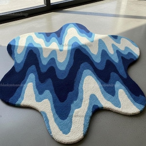 Hand-tufted wavy pattern rug in an irregular organic shape; ocean blue to navy blues with white cream, a textured plush melting rug.