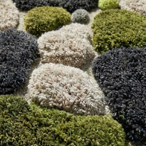 Modern hand-tufted beige wool rug with pebble pattern on balcony; 3D textured abstract carpet in gray, black, moss green.