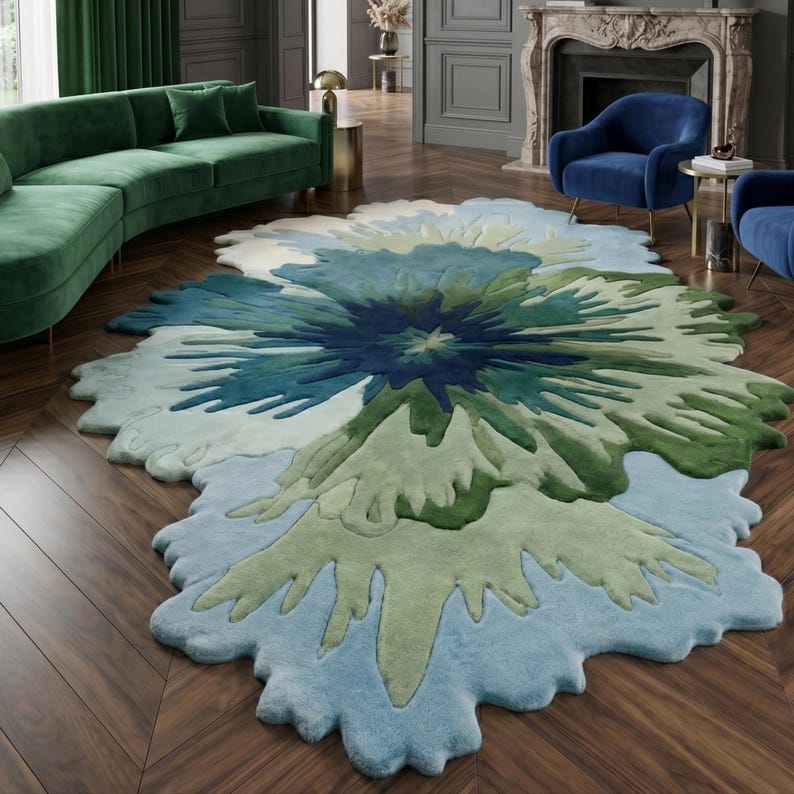 May include: A large, floral-shaped rug in shades of blue and green. The rug has a soft, textured appearance and is placed on a wooden floor. The design resembles a stylized flower, adding a decorative element to the room.