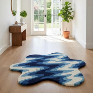 Hand-tufted wavy pattern rug in an irregular organic shape; ocean blue to navy blues with white cream, a textured plush melting rug.