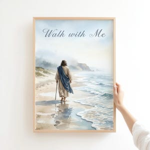 May include: Watercolor print in a light wooden frame. The artwork depicts a figure in a robe and blue shawl walking on a beach, with the text "Walk with Me" at the top. The ocean and shoreline are visible.