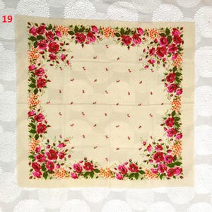 May include: A square, cream-colored scarf with a floral design. The scarf features a border of red roses and green leaves, with smaller pink floral accents scattered across the center. The number "19" is in the upper left corner.