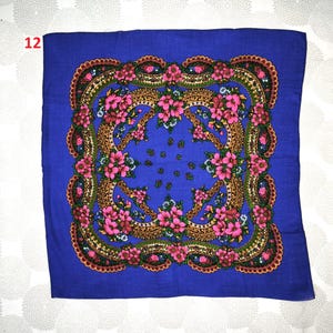Op de afbeelding: Een vierkante, blauwe sjaal met een bloemenmotief. De sjaal heeft een centraal patroon van roze bloemen en groene bladeren, omlijst door een goudbruine rand. De randen zijn versierd met een geschulpte rand. Het nummer "12" is zichtbaar in de linkerbovenhoek.