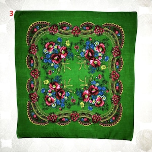 Op de afbeelding: Een vierkante, groene sjaal met een bloemenpatroon. De sjaal heeft een centraal patroon van rode en blauwe bloemen, omgeven door een decoratieve rand met rode en gele accenten. De sjaal is gemaakt van zachte stof.