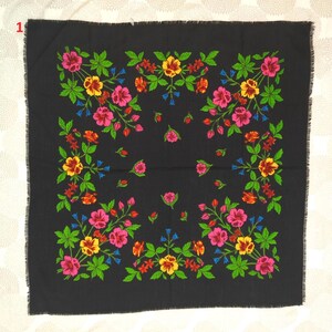 May include: A square black scarf with a floral pattern. The design features pink, yellow, and red flowers with green leaves and blue accents. The scarf has a fringed edge.