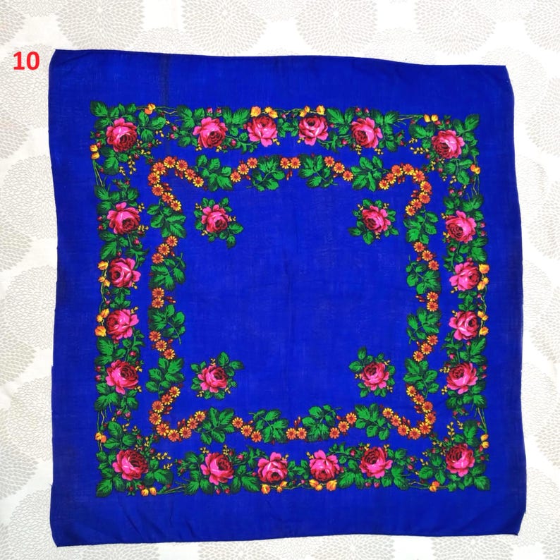 Op de afbeelding: Een vierkante, kobaltblauwe sjaal met een bloemenmotief. De rand heeft roze rozen, groene bladeren en oranje accenten. Het nummer "10" staat in de linkerbovenhoek. Deze sjaal is geschikt voor diverse gelegenheden.
