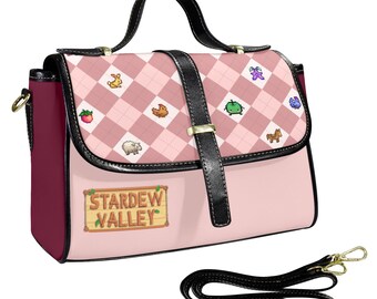 Peut inclure: Sacoche rose et bordeaux avec une poignée et une bandoulière noires. Le rabat présente un motif argyle rose avec des graphiques d'animaux de ferme de dessins animés. Le sac porte le texte "Stardew Valley" sur le devant.