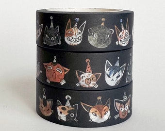 May include: Three rolls of black washi tape stacked on top of each other. Each roll features a repeating pattern of cartoon cat faces wearing party hats. The cat faces are in various colors and expressions.