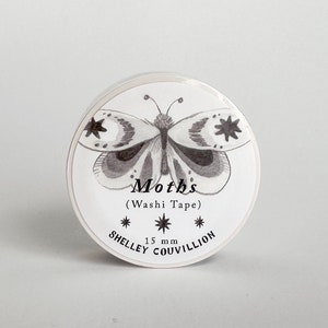 May include: A white roll of washi tape with a black and white illustration of a moth. The text "Moths (Washi Tape)" and "15 mm" are printed on the tape. The text "SHELLEY COUVILLION" is printed on the bottom of the tape.