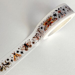 May include: White washi tape with a repeating pattern of brown and orange butterflies and black stars.