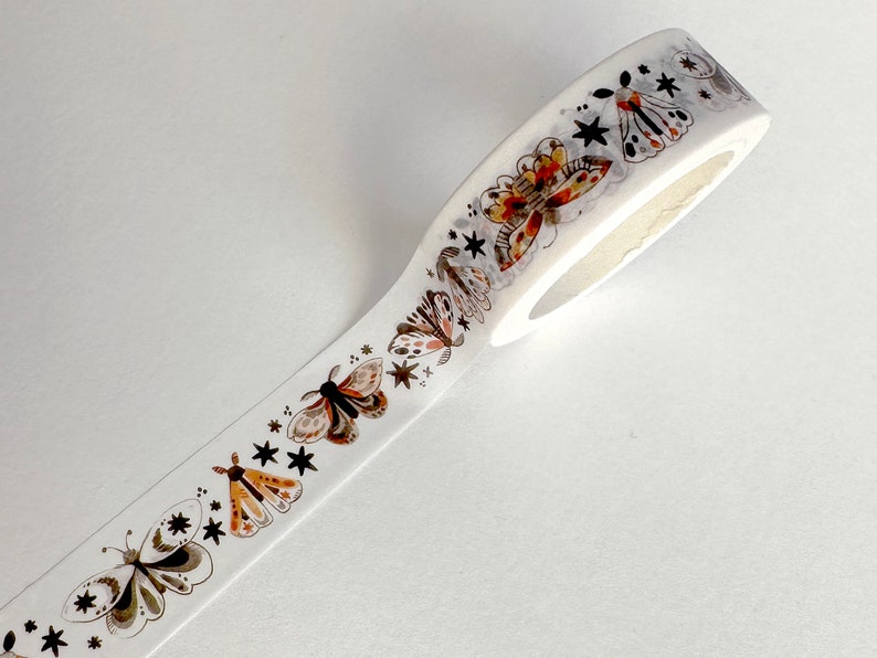 May include: White washi tape with a repeating pattern of brown and orange butterflies and black stars.