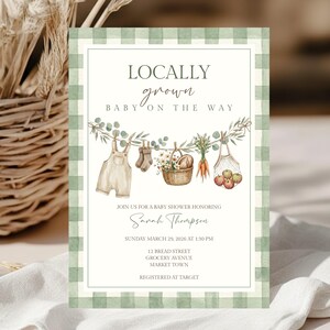 Op de afbeelding: Een babyshower-uitnodiging met een groene ruitjesrand en de tekst LOCALLY grown BABY ON THE WAY. Het ontwerp bevat aquarelillustraties van een tuinbroek, sokjes, een mand met bloemen, wortels en appels die aan een waslijn hangen.