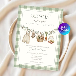 Op de afbeelding: Een uitnodigingskaart voor een babyshower met een groen-witte ruitjesrand. De tekst luidt LOCALLY grown BABY ON THE WAY. Een illustratie toont een waslijn met baby-tuinbroekjes, sokjes, een mand met bloemen, wortels en appels in een nettas.