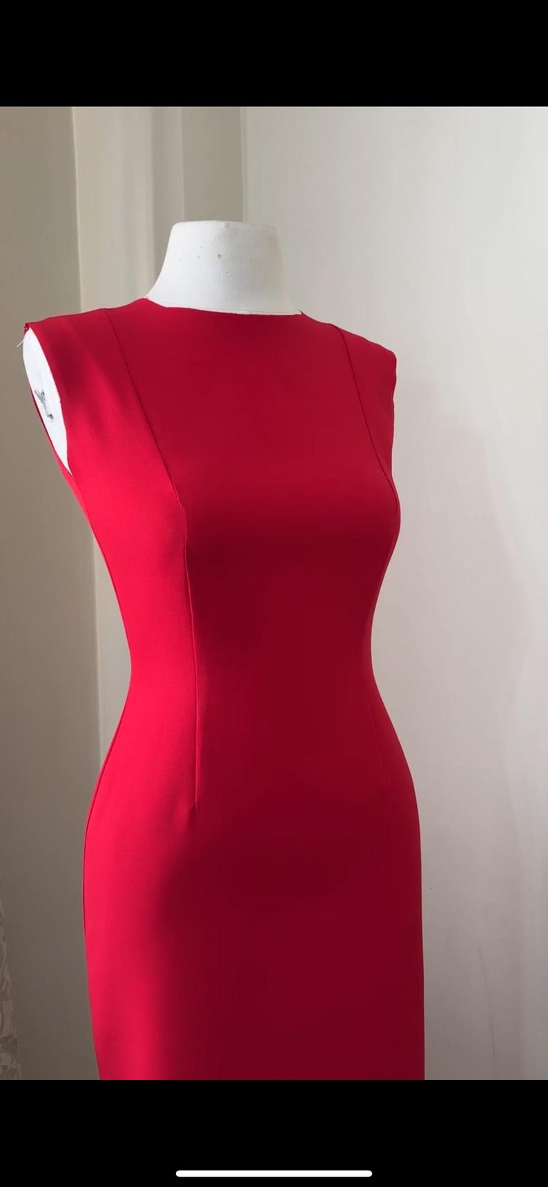 K&ouml;nnte beinhalten: Ein leuchtend rotes, &auml;rmelloses Kleid auf einer Schaufensterpuppe. Das Kleid hat eine figurbetonte Silhouette, einen runden Ausschnitt und eine Naht am R&uuml;cken. Das Kleid ist aus einem glatten, einfarbigen Stoff gefertigt.