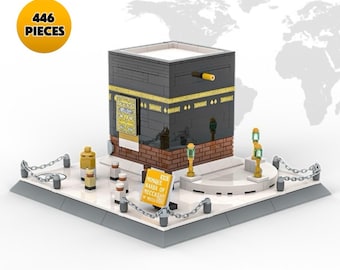 Puede incluir: Modelo de la Kaaba en La Meca, construido con 446 piezas. La estructura negra y dorada se asienta sobre una plataforma blanca, rodeada de pequeñas figuras y una cadena. Un letrero dice "Mezquita Kaaba de La Meca".