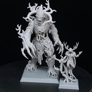 May include: A gray, 3D-printed fantasy miniature set featuring a large, tree-like creature with antlers and a smaller figure in a hooded cloak. The figures are on square bases, set against a dark background.