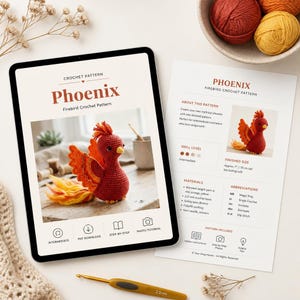 May include: A crochet pattern titled "Phoenix Firebird Crochet Pattern" displayed on a tablet and a printed sheet. The pattern includes instructions for creating a red and orange amigurumi phoenix. A crochet hook and yarn balls are also visible.