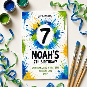 Op de afbeelding: Een rechthoekige verjaardagsuitnodiging met een witte achtergrond en blauwe, groene en gele verfspatten. De tekst luidt: YOU'RE INVITED! 7 NOAH'S 7TH BIRTHDAY! SATURDAY, JUNE 16TH AT 3PM 214 PAINT LANE RSVP. Penselen en linten liggen eromheen.