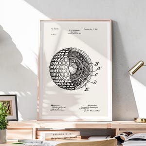 May include: A framed black and white diagram of a golf ball's internal structure. The diagram is labeled with letters and numbers, and includes the text "B. CAVAMAGH GOLF BALL" and "Patented Oct. 7, 1992."