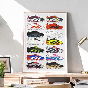 May include: A framed print featuring a collection of colorful soccer cleats. The cleats are arranged in rows, showcasing various designs with accents of red, blue, yellow, and black. The artwork is displayed on a wooden desk.