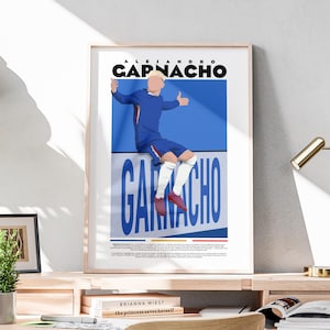 Könnte beinhalten: Gerahmter Kunstdruck mit einer stilisierten Illustration eines Fußballspielers in blauem Trikot. Der Spieler sitzt mit ausgestreckten Armen, über dem Namen "CAPNACHO" in fetten Buchstaben. Der Name "GARNACHO" ist ebenfalls sichtbar. Der Druck wird auf einer Holzoberfläche angezeigt.