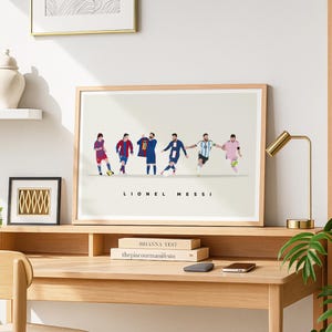 May include: Framed art print featuring a minimalist illustration of Lionel Messi in various soccer poses. The artwork showcases Messi in different team uniforms, with the name "Lionel Messi" printed below the figures. The frame is light brown.
