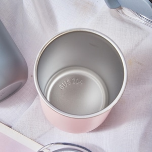 May include: A pink insulated tumbler with a silver interior and a clear lid with a gray silicone piece. The bottom of the tumbler is stamped with "SUS 304". Other tumblers and lids are visible.