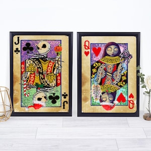 May include: Two framed playing card art prints featuring characters from The Nightmare Before Christmas. One shows Jack Skellington as the Jack of Clubs, the other Sally as the Queen of Hearts. The cards have a vintage, distressed look.
