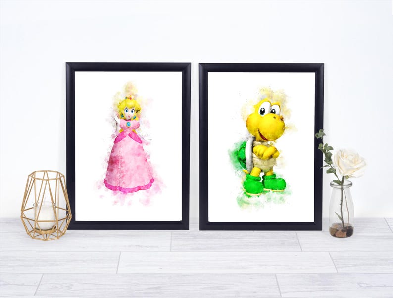 May include: Two framed watercolor prints featuring characters from a video game. One print shows a princess in a pink dress, and the other depicts a turtle-like character in green and yellow. The prints are in black frames.