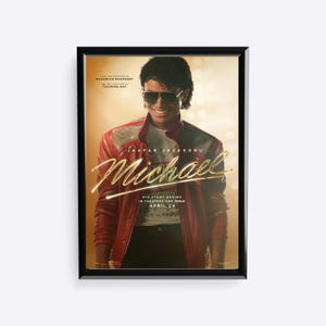 May include: Framed movie poster featuring Jaafar Jackson as Michael Jackson. The poster has a warm, golden background with the title "Michael" in gold script. The actor wears a red jacket and sunglasses. Text at the bottom reads "His story begins in theaters and IMAX April 24."