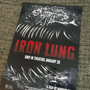 Op de afbeelding: Een filmposter voor "Iron Lung" met een donker, onheilspellend ontwerp. De titel staat in vette rode letters, met een skeletachtige illustratie erboven. De tekst "Only in Theaters January 30" is ook zichtbaar. De poster heeft een R-classificatie.