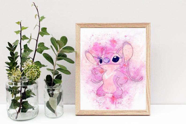 Peut inclure: Une impression encadr&eacute;e &agrave; l'aquarelle repr&eacute;sentant un personnage de dessin anim&eacute; rose avec de grandes oreilles et des yeux bleu fonc&eacute;. L'&oelig;uvre est pos&eacute;e sur un fond rose &agrave; l'aquarelle avec des &eacute;claboussures de couleur. Le cadre est en bois clair.