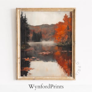 Könnte beinhalten: Ein Herbstlandschaftsgemälde mit einem ruhigen See, der leuchtend orange und rote Bäume widerspiegelt. Dunkelgrüne Kiefern stehen links, mit einer nebligen Atmosphäre. Das Kunstwerk ist in einem goldfarbenen, verzierten Rahmen gerahmt. Der Text "WynfordPrints" steht unten.