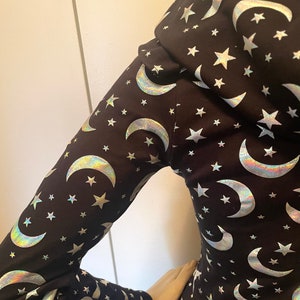 Op de afbeelding: Zwart langarm shirt met een zilveren, iriserende maan- en sterrenprint.