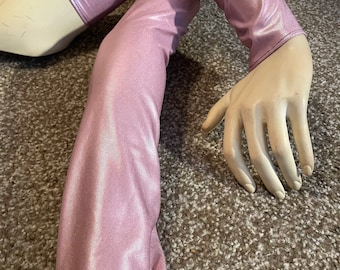 Op de afbeelding: Een paar lange, roze, glanzende armwarmers van rekbaar materiaal. De armwarmers zitten op een mannequinarm.