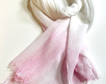 May include: A white and pink ombre scarf with a frayed edge. The scarf is made of a soft, lightweight fabric.