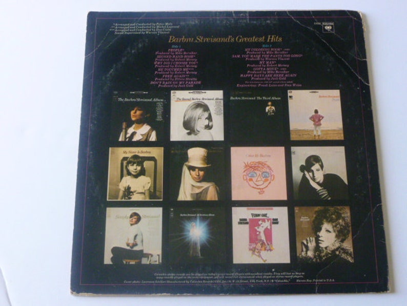 May include: A black and white vinyl record album cover featuring a collage of photos of a woman with different hairstyles and outfits. The album title is "Barbra Streisand's Greatest Hits" and the album cover includes the text "Side 1" and "Side 2".