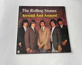 Puede incluir: Portada de álbum vintage de "Around And Around" de The Rolling Stones. La portada presenta una foto grupal de los miembros de la banda con trajes. El título del álbum está en texto blanco y amarillo sobre un fondo marrón.