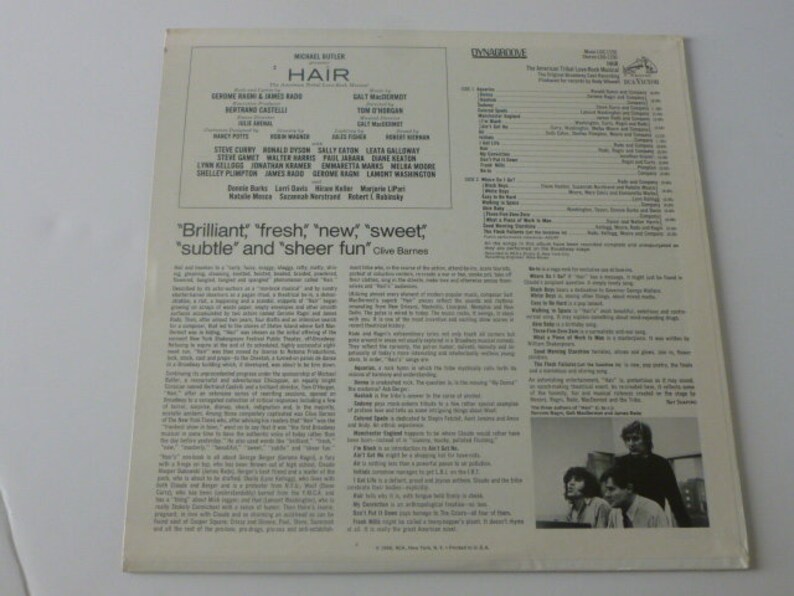 May include: A vintage record album cover for the musical "Hair" featuring a cast photo of the actors. The album cover is white with black text and a photo of the cast in the bottom right corner. The text on the cover reads "Hair" and "Michael Butler".