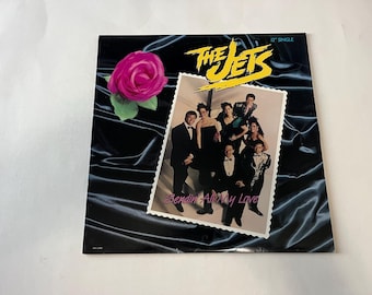 May include: A 12" single record by The Jets, featuring a photo of the band in formal attire. The record cover is black with a pink rose and the title "Sendin' All My Love" in white.