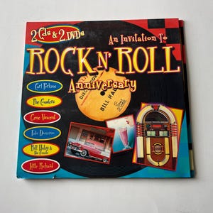 May include: A blue and yellow book cover with the title "Rock 'n' Roll Anniversary" and a picture of a vintage jukebox. The cover also features a record with the names of artists like Carl Perkins, The Coasters, Gene Vincent, and Little Richard.