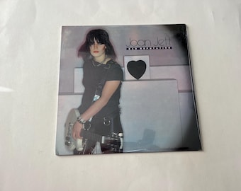 May include: A black and white album cover featuring a woman with dark hair playing a white electric guitar. The album title is "Joan Jett Bad Reputation".