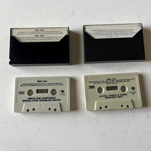May include: Two cassette tapes, one labeled "Simon and Garfunkel Bridge Over Troubled Water" and the other labeled "Blood, Sweat & Tears Greatest Hits".