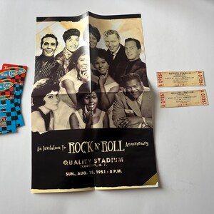 May include: A black and white poster advertising a Rock 'n' Roll Anniversary at Quality Stadium in Flushing, NY on August 15, 1951. The poster features a group of people, including singers and musicians, with the text "An Invitation to Rock 'n' Roll Anniversary" and "Quality Stadium Flushing, N.Y. Sun., Aug. 15, 1951 - 8 P.M."